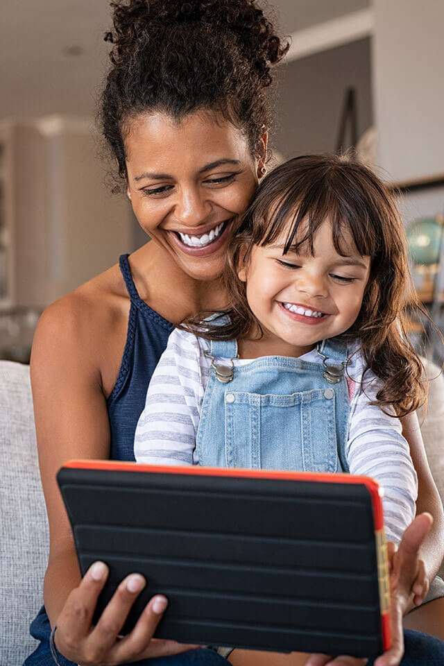 mother and daughter laughing at their tablet