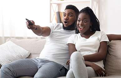 Couple on couch watching TV with remote