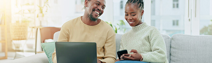 a couple happily on their laptop and smart phone